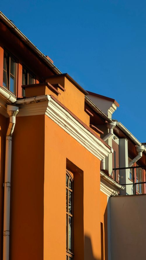 Free Stunning view of a modern building with an orange facade against a clear blue sky. Stock Photo