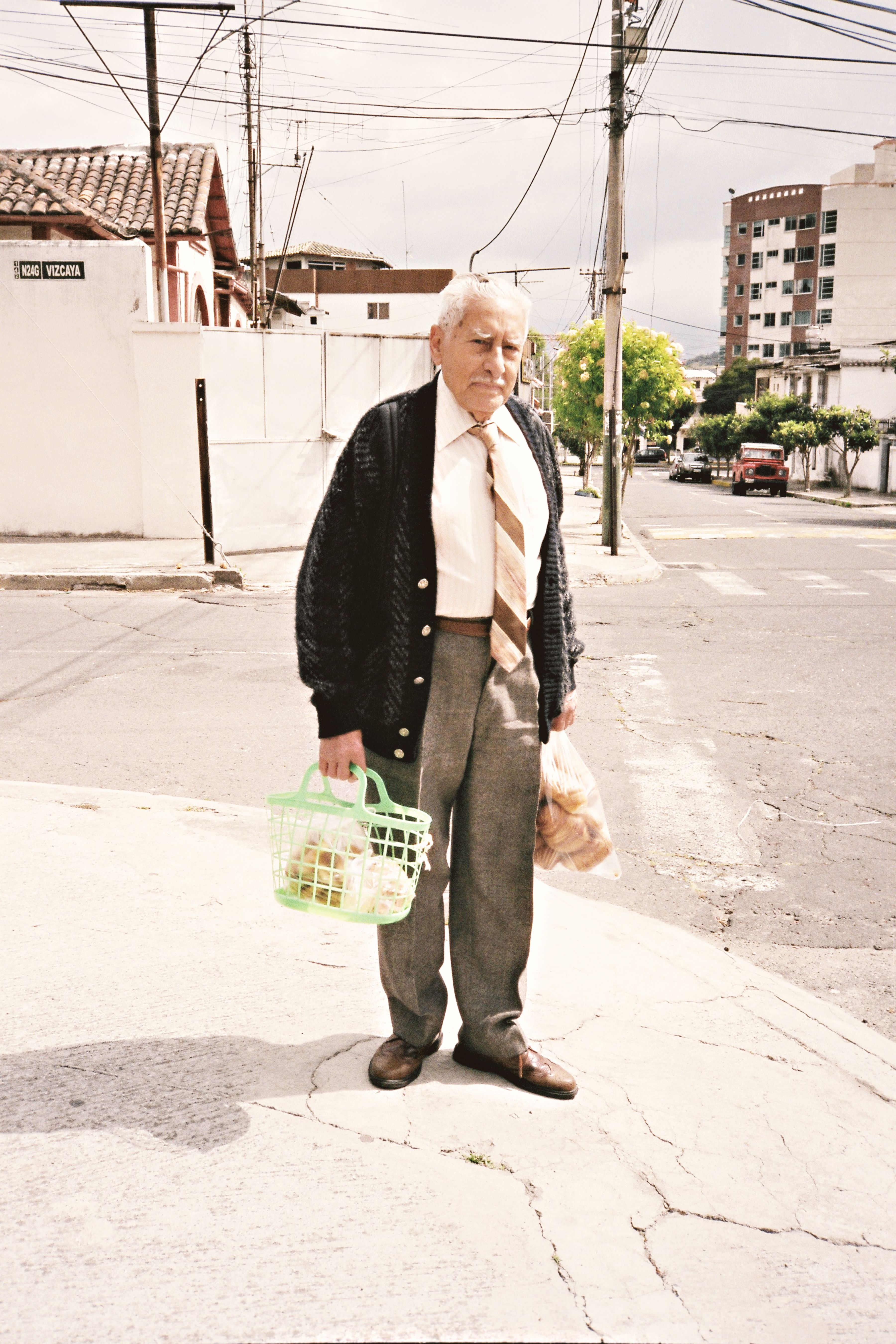 Senior man carrying groceries on an urban street in Quito, Ecuador.