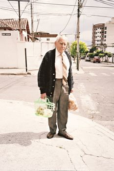 Senior man carrying groceries on an urban street in Quito, Ecuador.