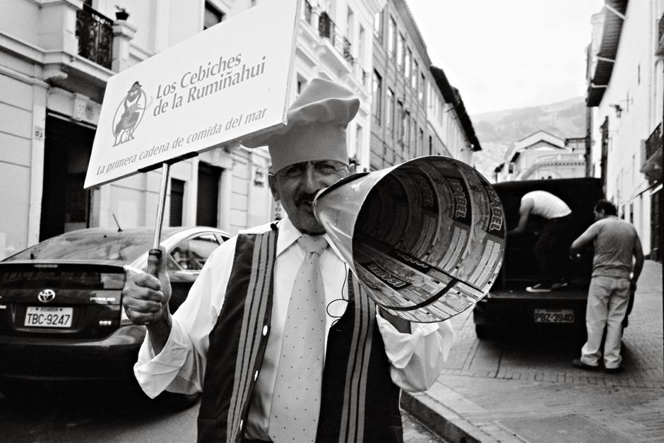 A chef promoting a seafood restaurant in Quito's historic center with a megaphone.