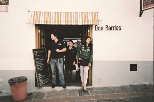Entrance of Dos Barrios cafe in Quito, Ecuador with smiling staff welcoming customers.