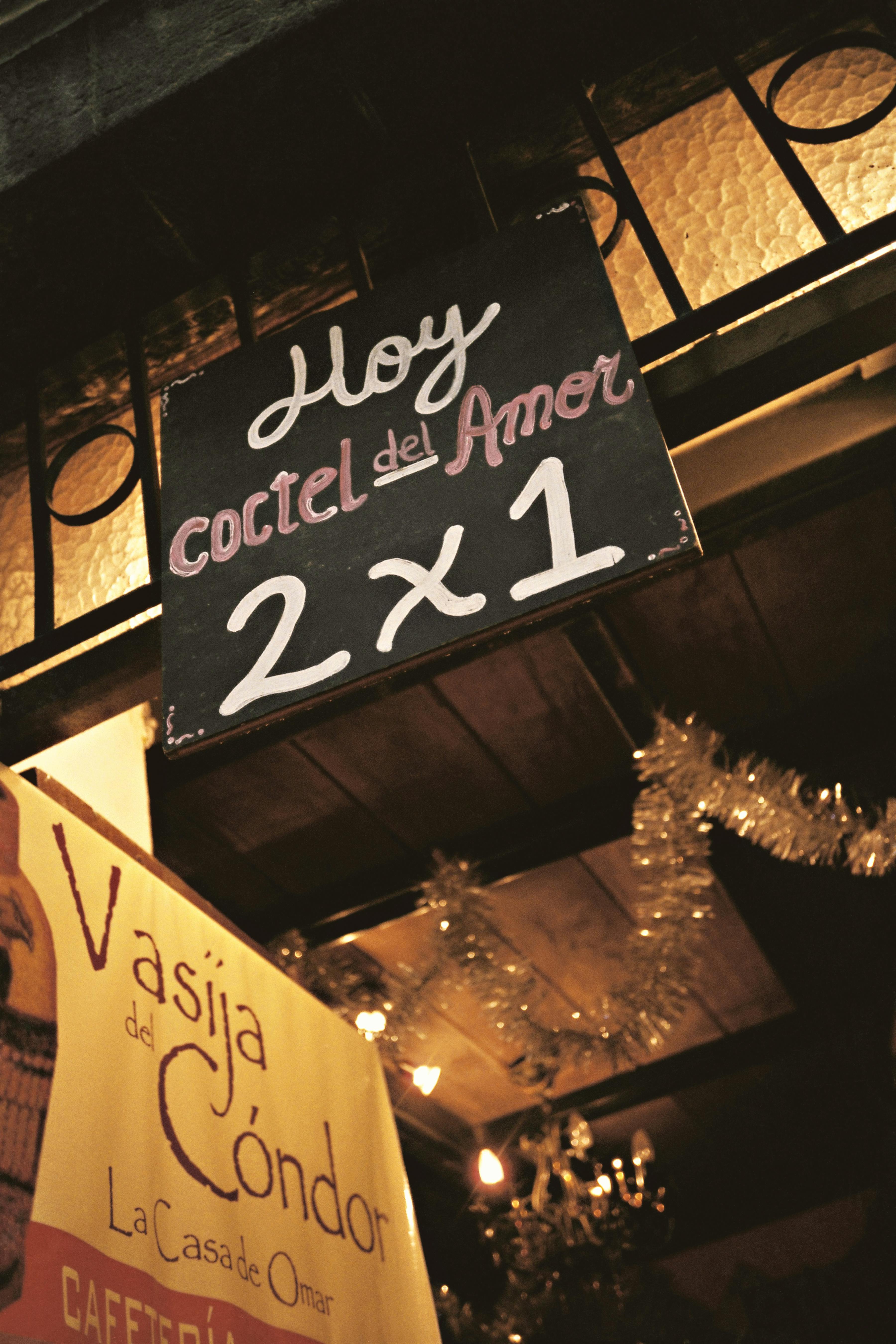 Chalkboard sign promoting cocktails with a 2 for 1 offer at a Quito venue.