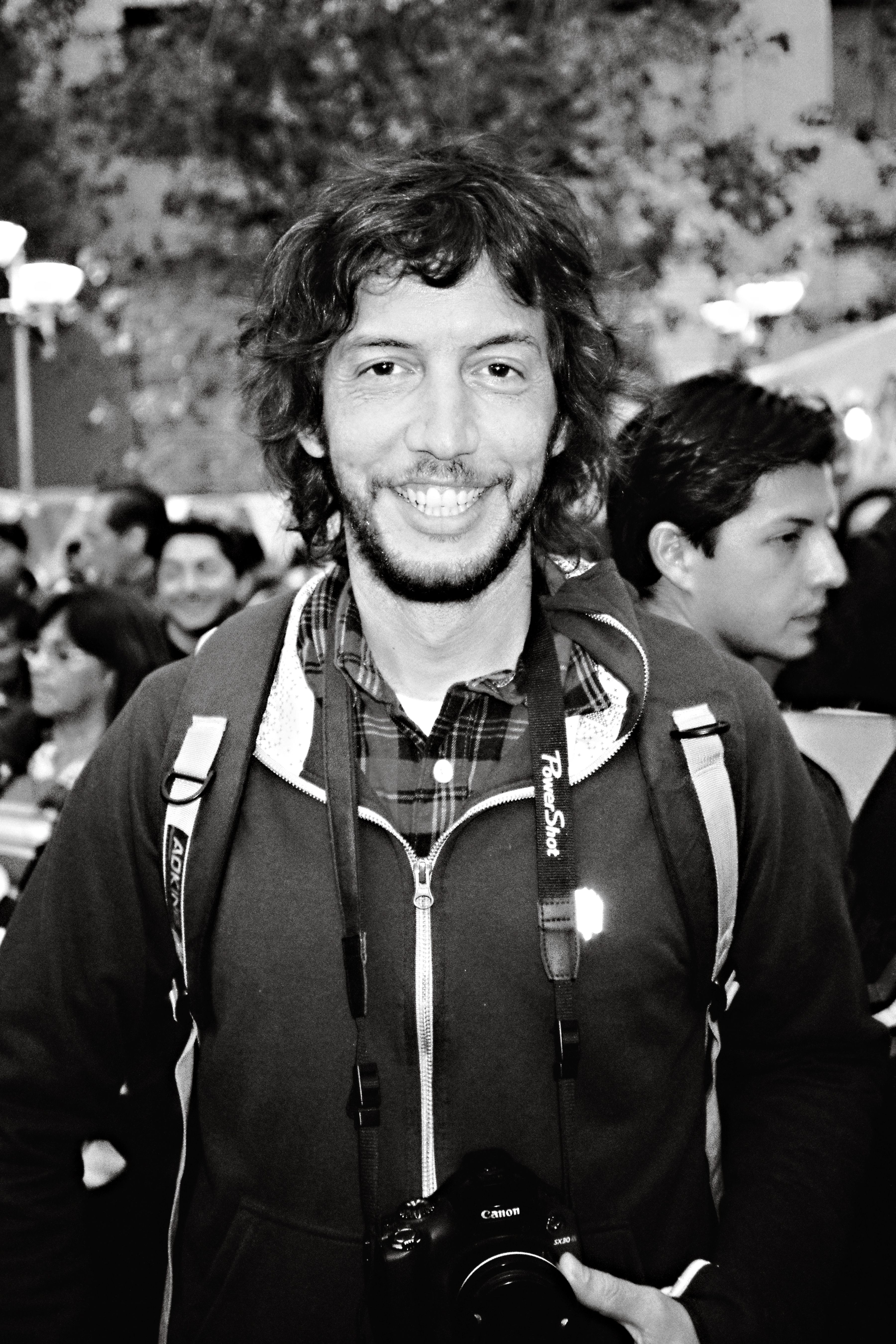 Black and white candid photo of a smiling photographer in Quito's bustling streets.
