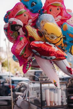 Vibrant helium balloons featuring popular cartoon characters and vehicles at an outdoor stall.
