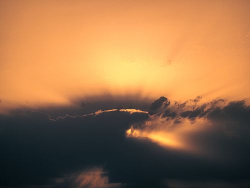 Free Stunning view of a sunset with dark clouds creating a silhouette effect against an orange sky. Stock Photo