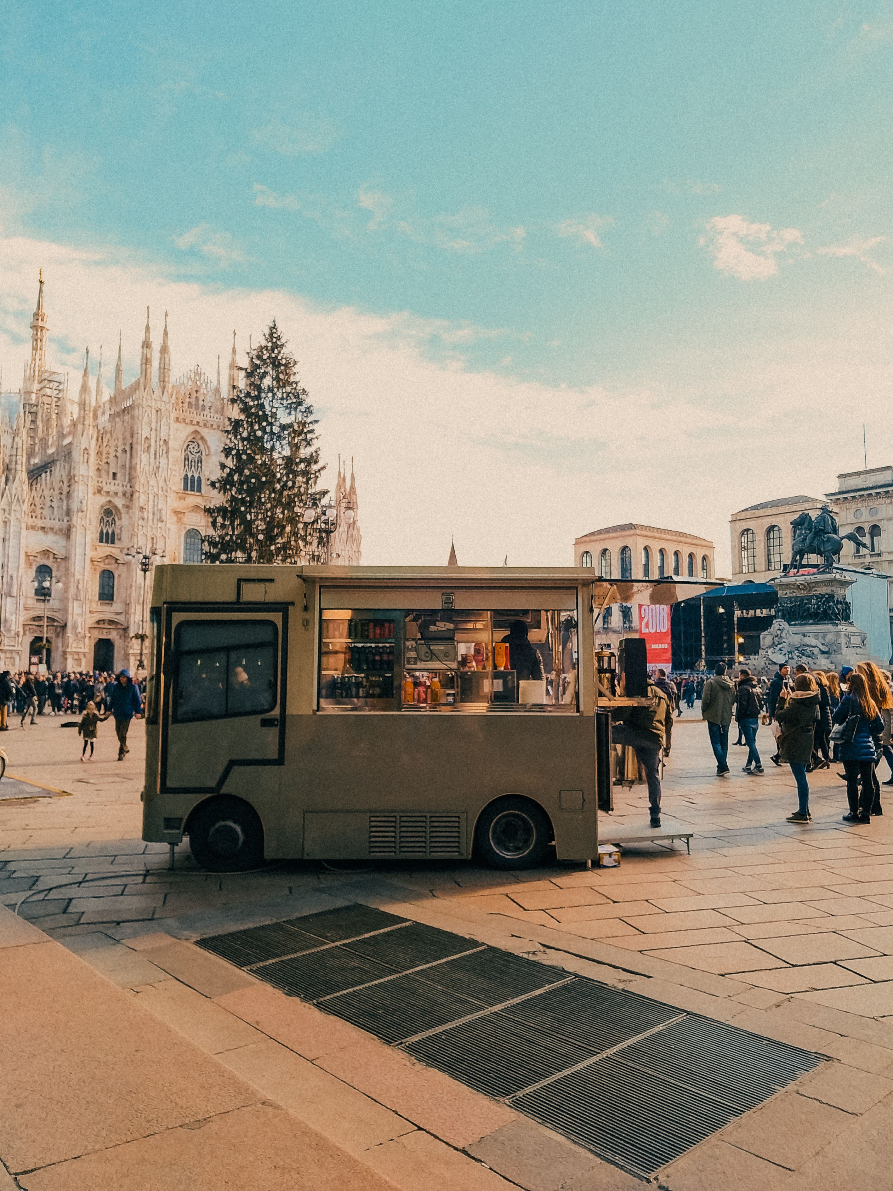 Busy day at Piazza del Duomo with a food truck and vibrant crowd in Milan, Italy.