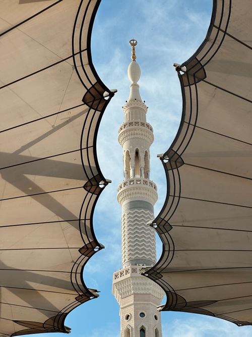 Free Captivating view of a mosque minaret framed by large architectural umbrellas in Medina, Saudi Arabia. Stock Photo