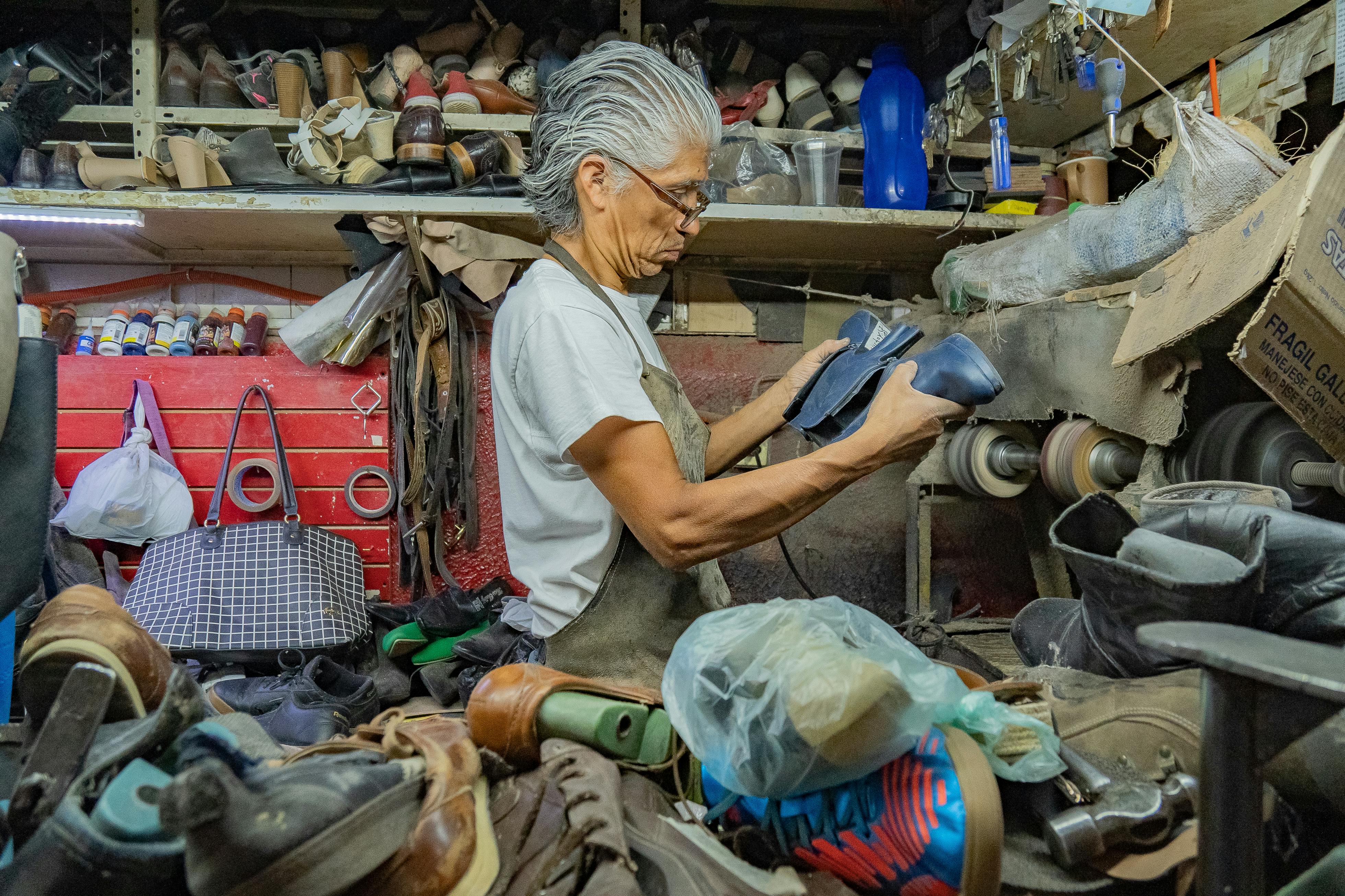Elderly cobbler crafting shoes in a traditional workshop in Guanajuato, Mexico.