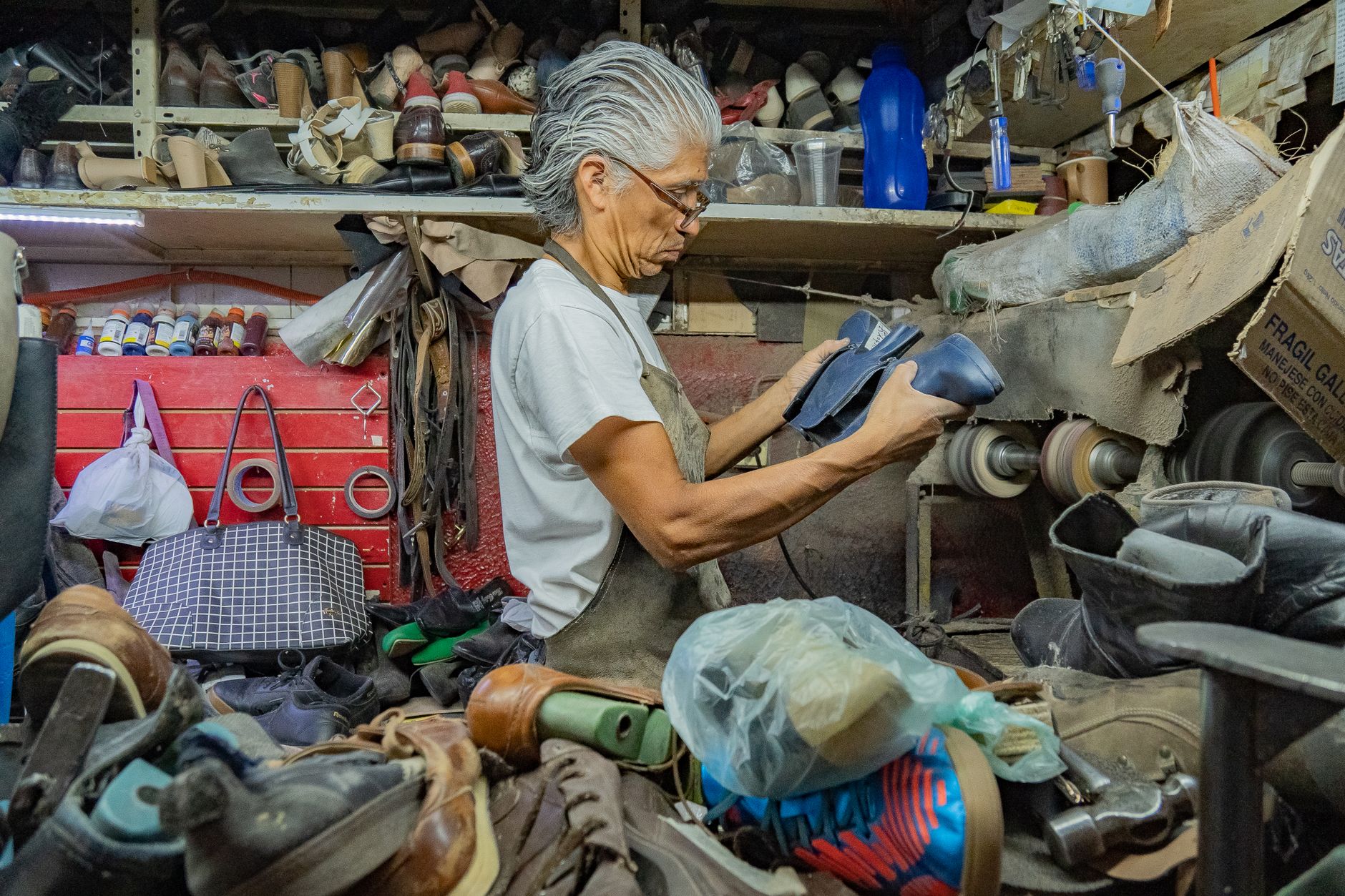 Elderly cobbler crafting shoes in a traditional workshop in Guanajuato, Mexico.