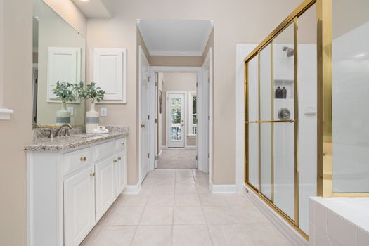 Bright and spacious modern bathroom featuring a gold shower frame and sleek vanity.