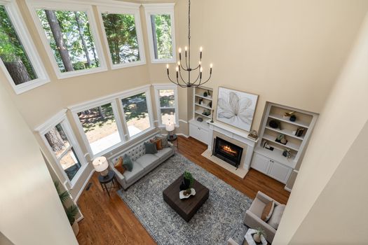 Spacious living room featuring large windows, a chandelier, and a cozy fireplace.