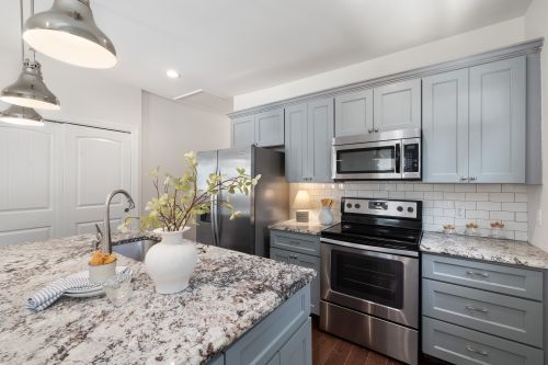 Free A stylish kitchen featuring granite countertops, stainless steel appliances, and elegant pendant lighting. Stock Photo