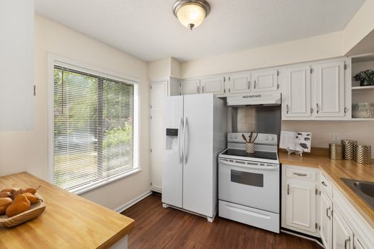 Bright white kitchen with wooden countertops and contemporary appliances, perfect blend of modern and classic design.