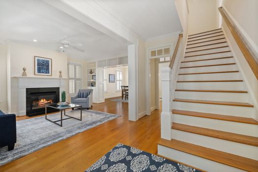A modern living room featuring a cozy fireplace and elegant decor with a view of the dining area.