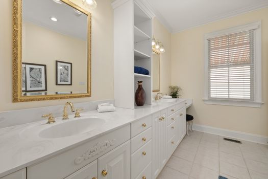 Spacious bathroom with a double vanity, gold accents, and stylish decor creating a luxurious ambiance.