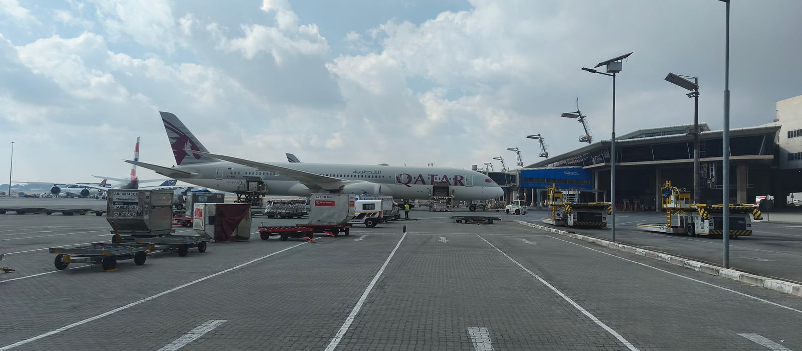 Qatar Airways aircraft on tarmac at Johannesburg Airport with service vehicles