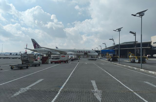 Qatar Airways aircraft on tarmac at Johannesburg Airport with service vehicles — arriving in Johannesburg