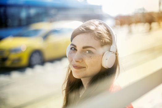 Happy young woman in headphones listening to music on street