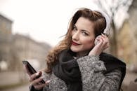 一位年轻女子在冬天户外微笑着听音乐