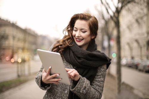 Free Smiling woman using a tablet on a chilly day, embracing technology with joy. Stock Photo