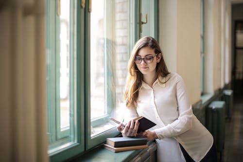 Free Woman in White Long Sleeve Shirt While Reading a Book Stock Photo
