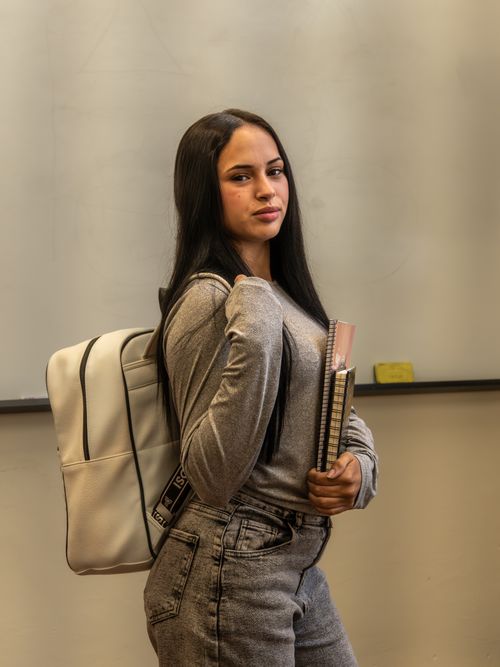 Free Young woman with backpack in classroom setting, Montevideo. Stock Photo