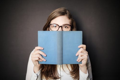 Free Woman in White Long Sleeve Shirt Holding Blue Book Stock Photo