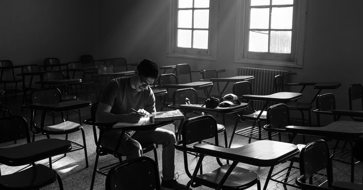 A student studies alone in a sunlit Argentine classroom, suggesting focus and solitude.