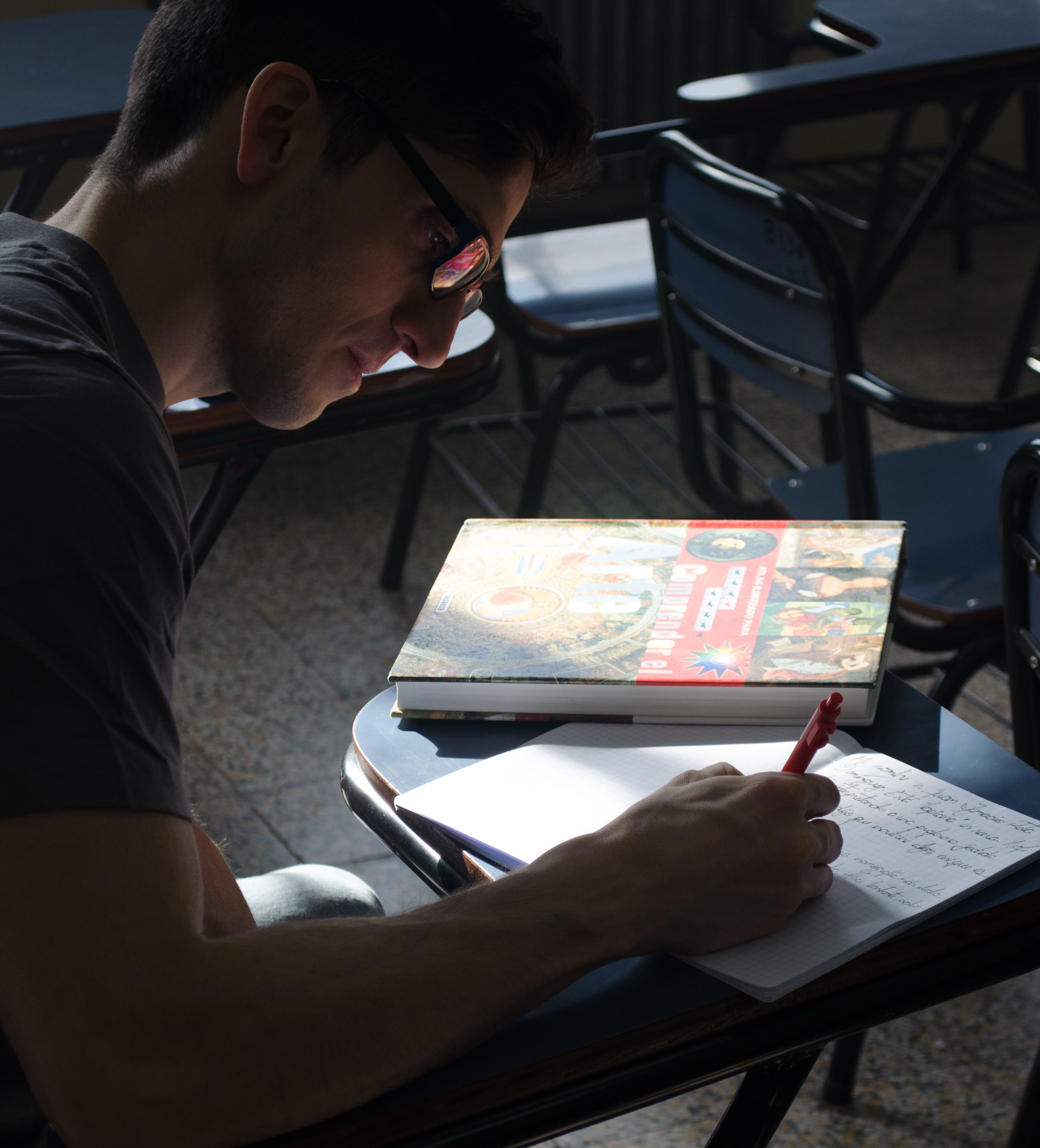 A university student writing notes in a bright Buenos Aires classroom.