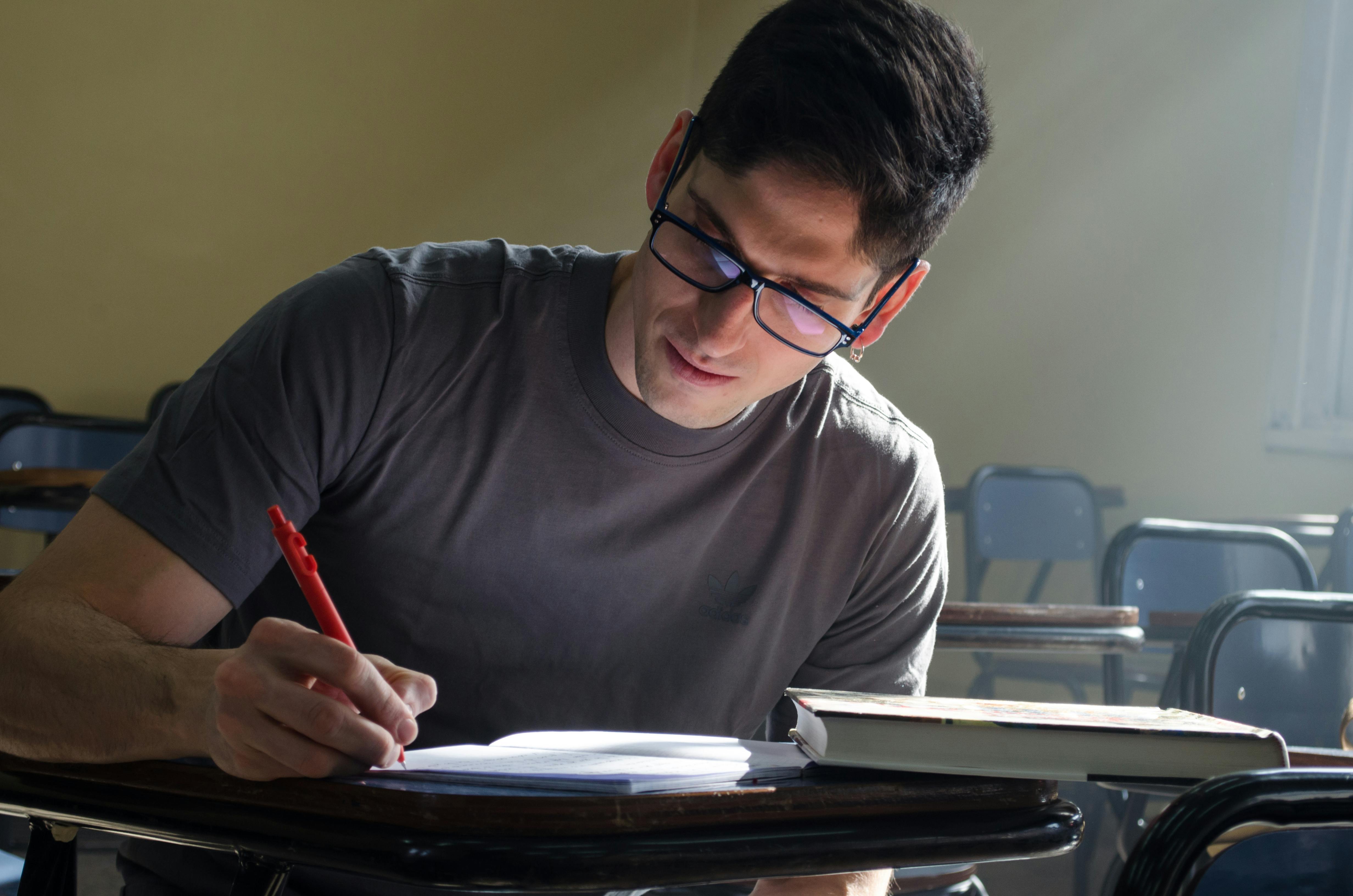 Focused student studying at a desk in a classroom with natural light streaming in.