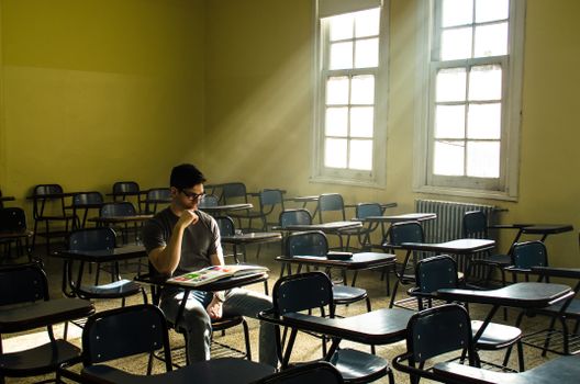 A lone student studies in a sunlit, empty classroom in Buenos Aires, Argentina.