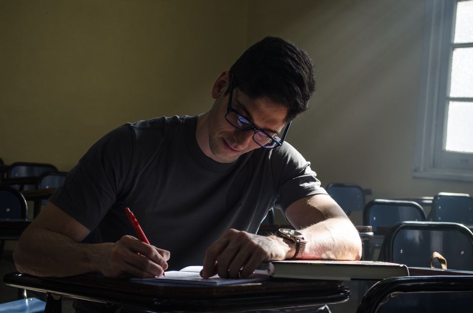 Young man studying in a sunlit classroom in Buenos Aires, Argentina, emphasizing focus and concentration. Young man studying in a sunlit classroom in Buenos Aires, Argentina, emphasizing focus and concentration.