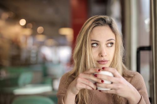 Free A woman in deep thought while holding a cup of coffee indoors. Stock Photo