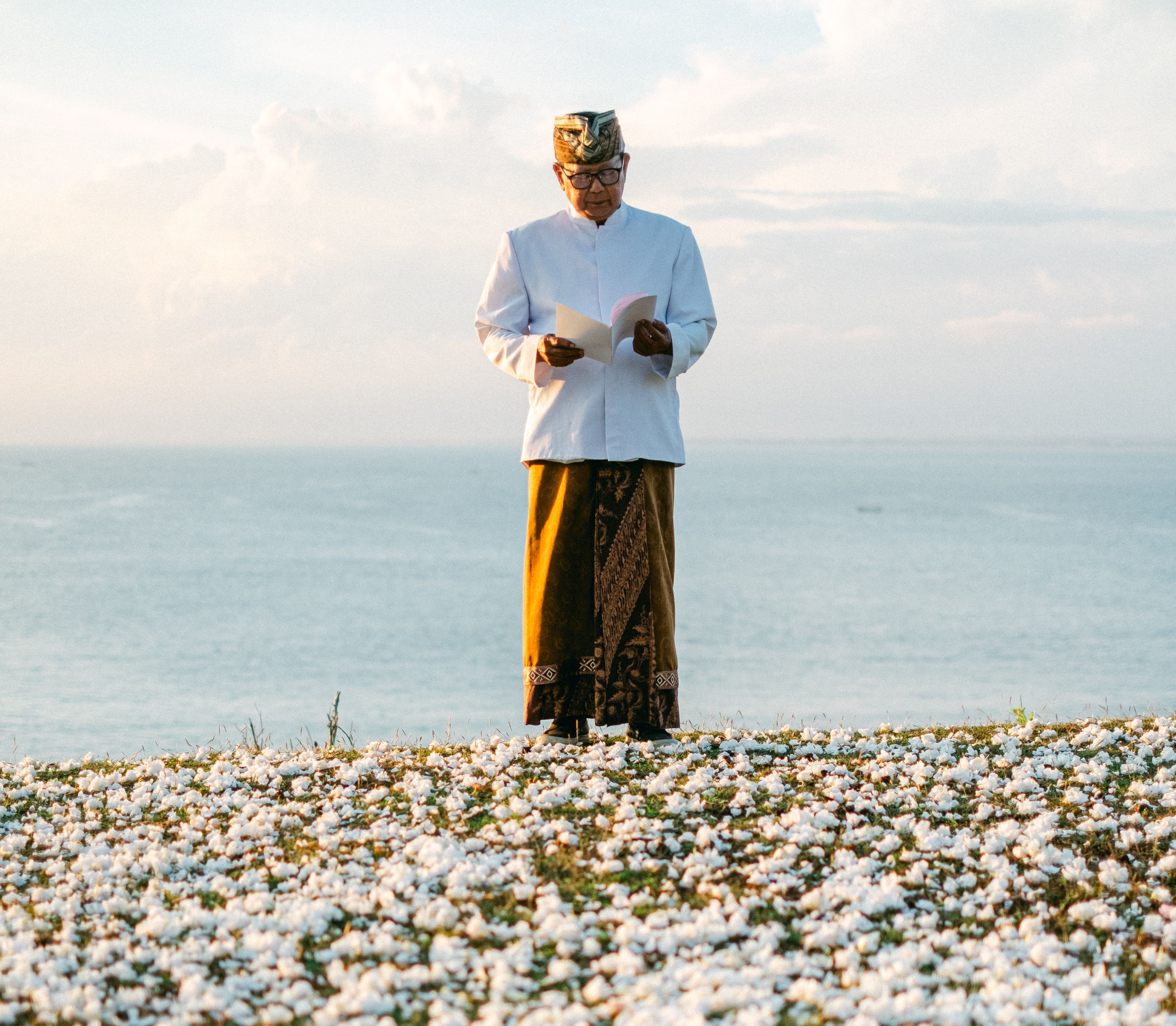 Clifford Geertz studying Balinese cockfight notes beside a crowded village arena in Bali