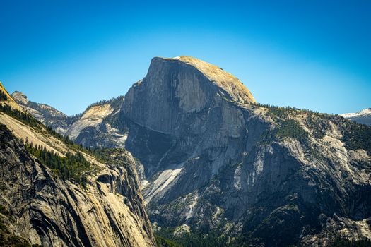 Majestic Half Dome rock formation in Yosemite under a clear blue sky, showcasing rugged beauty.