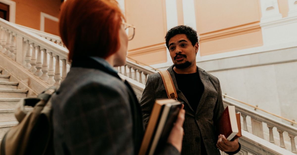 Two university students engaged in conversation on a classroom staircase.