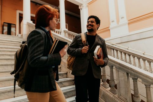 Free Two university students engaged in conversation on elegant marble stairs in Buenos Aires. Stock Photo