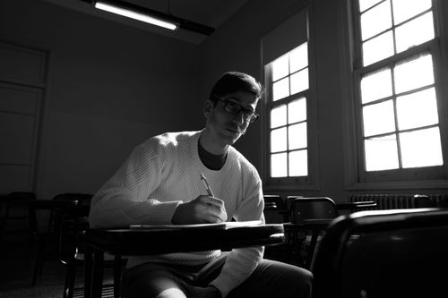 Free University student writing in a classroom with dramatic lighting in Buenos Aires. Stock Photo