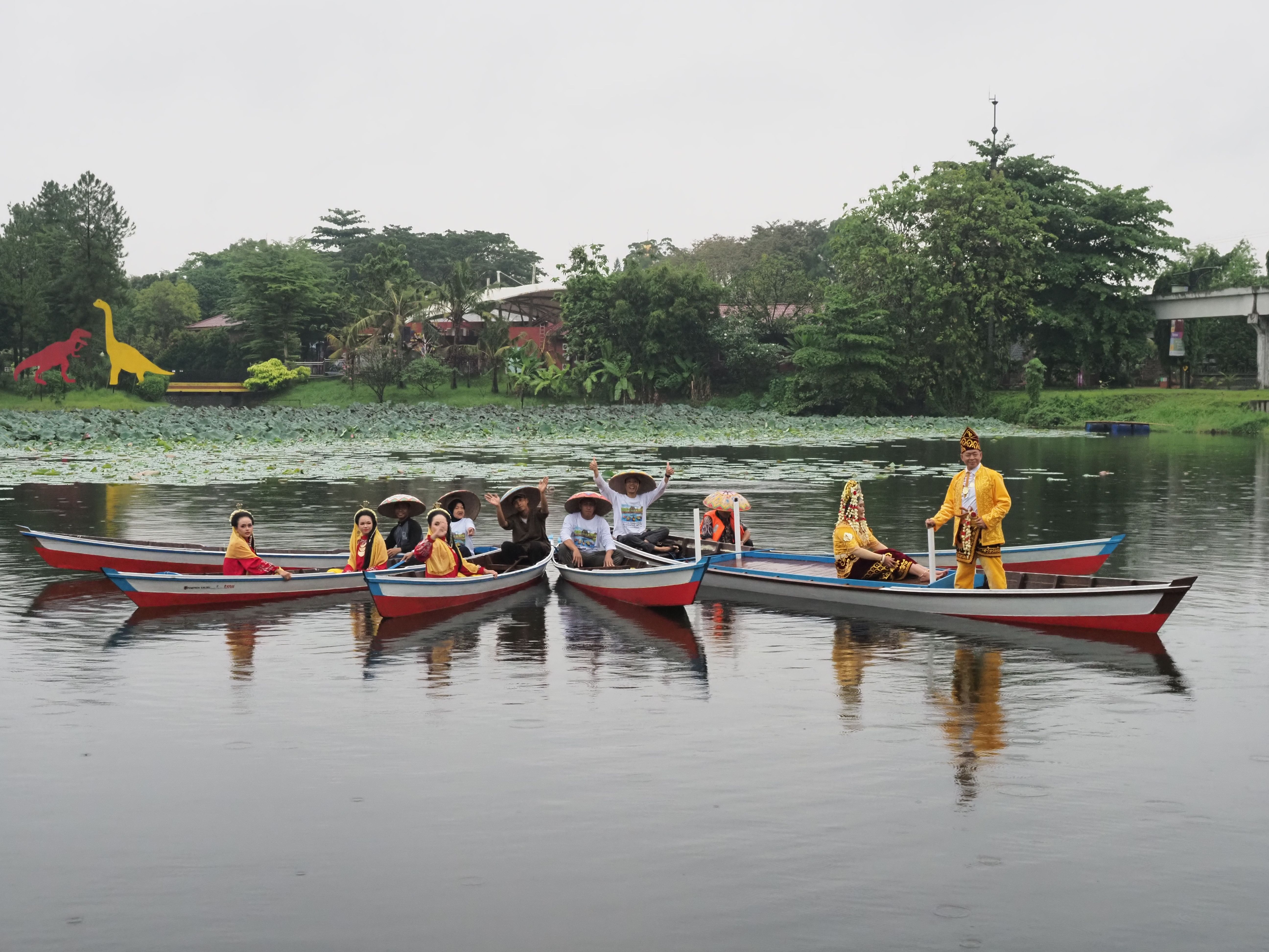 Group of people in traditional attire on boats in Jakarta lake.