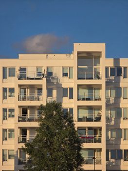 A contemporary apartment building with multiple balconies under clear blue skies.
