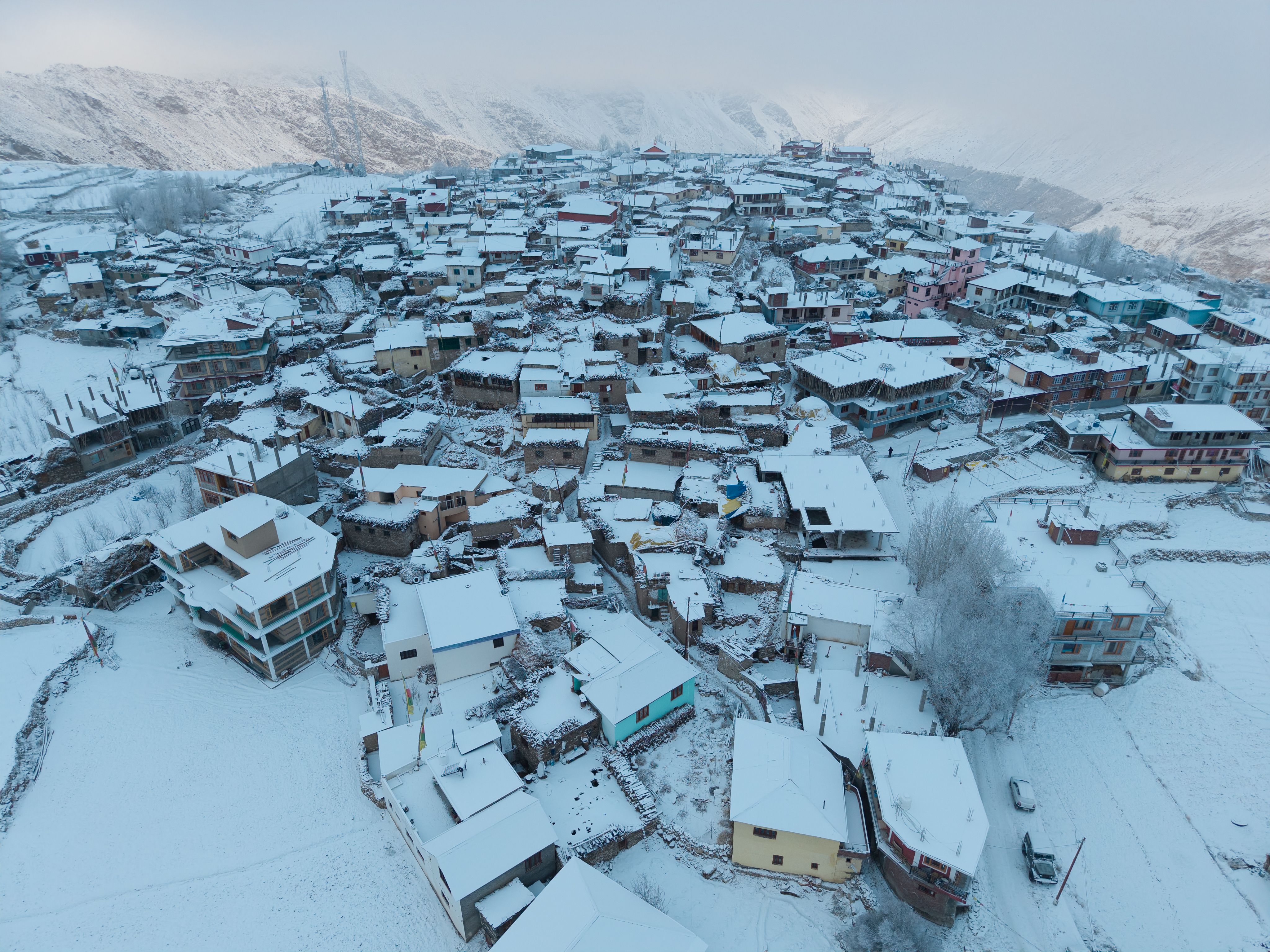 Aerial panorama of snow-covered Marango Rangarik village in Himachal Pradesh, showcasing traditional architecture in winter.