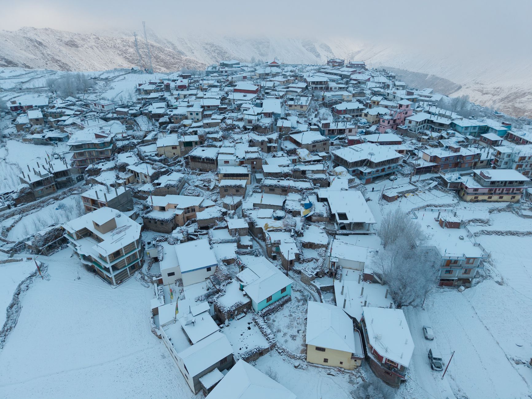 Aerial panorama of snow-covered Marango Rangarik village in Himachal Pradesh, showcasing traditional architecture in winter.