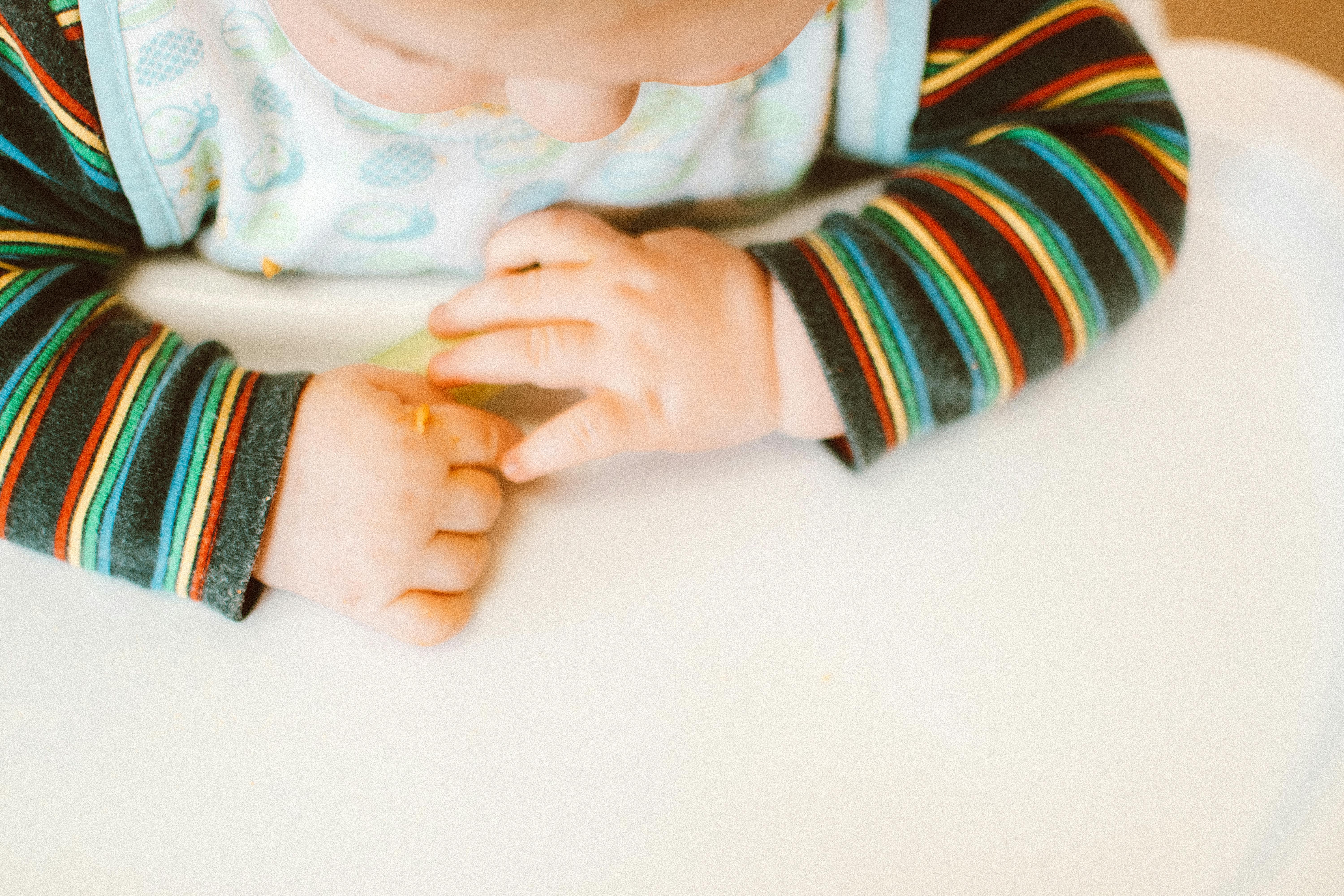 photo of kid wearing colorful long sleeves sitting on high chair