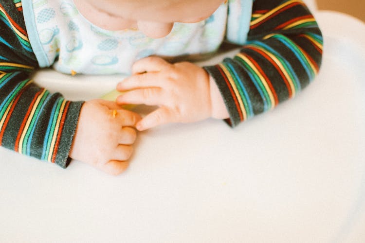 Photo Of Kid Wearing Colorful Long Sleeves Sitting On High Chair