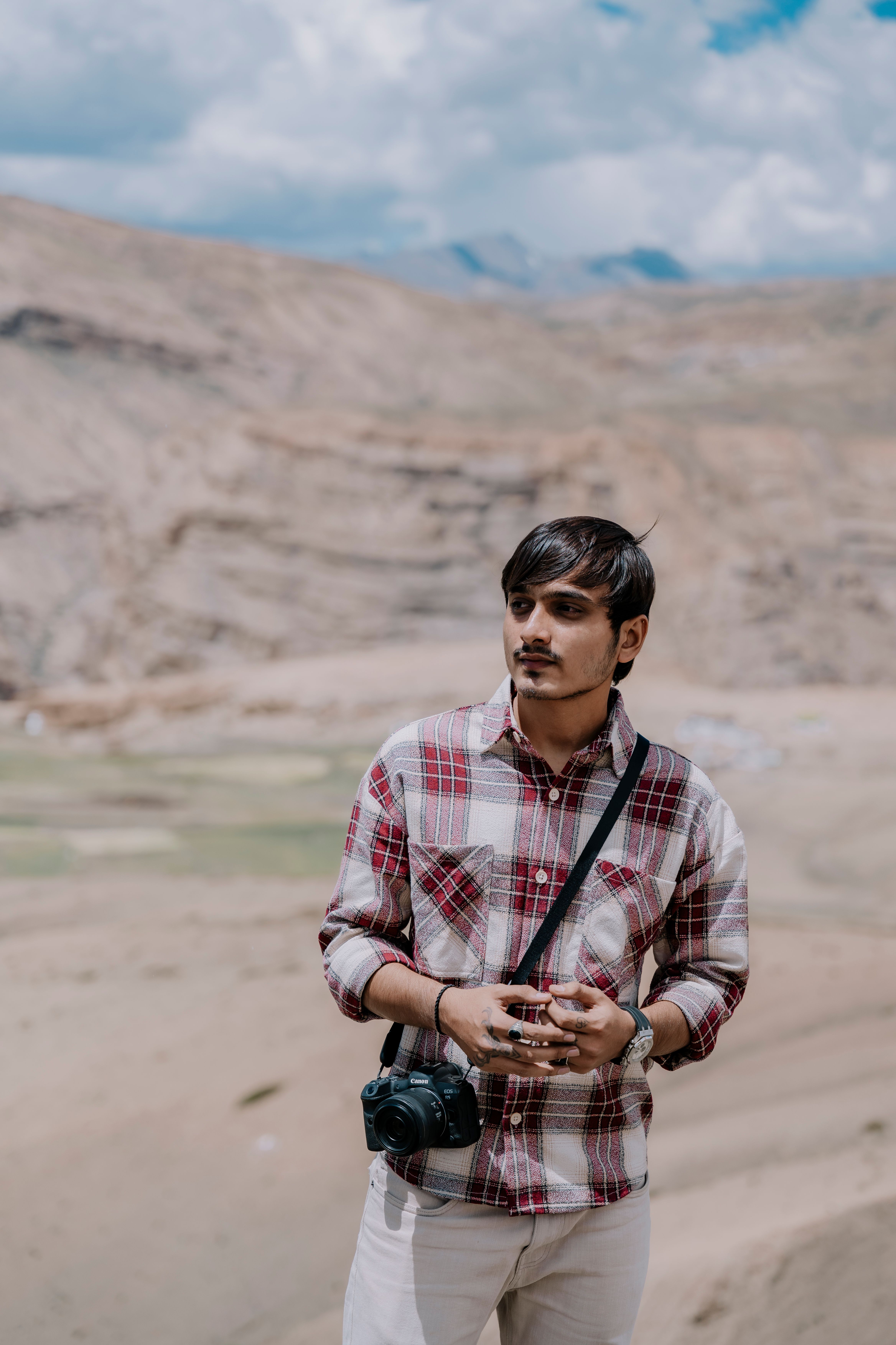 Portrait of a young photographer with a camera in a desert landscape under a bright sky.
