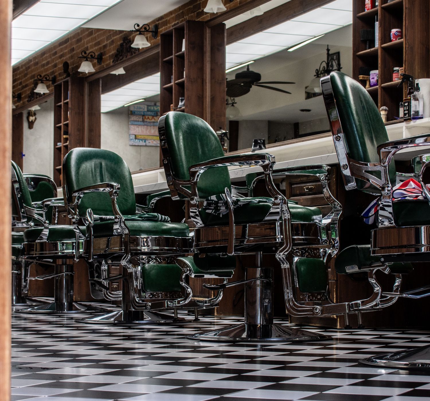 Charming vintage barber shop with classic green chairs and checkered floor tiles.