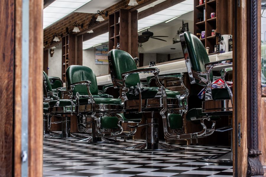 Sillas de barbería verdes sobre suelo de ajedrez