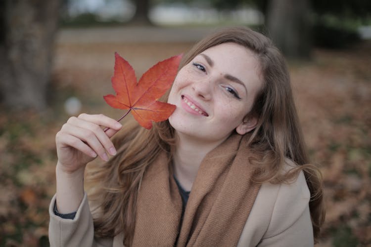 Happy Millennial Woman With Red Leaf Enjoying Autumn In Park