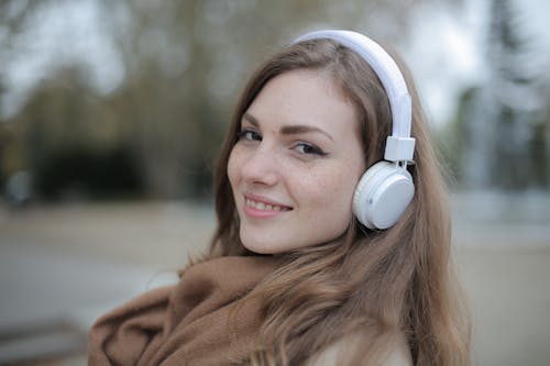 Free Joyful millennial woman in headphones listening to music in park Stock Photo