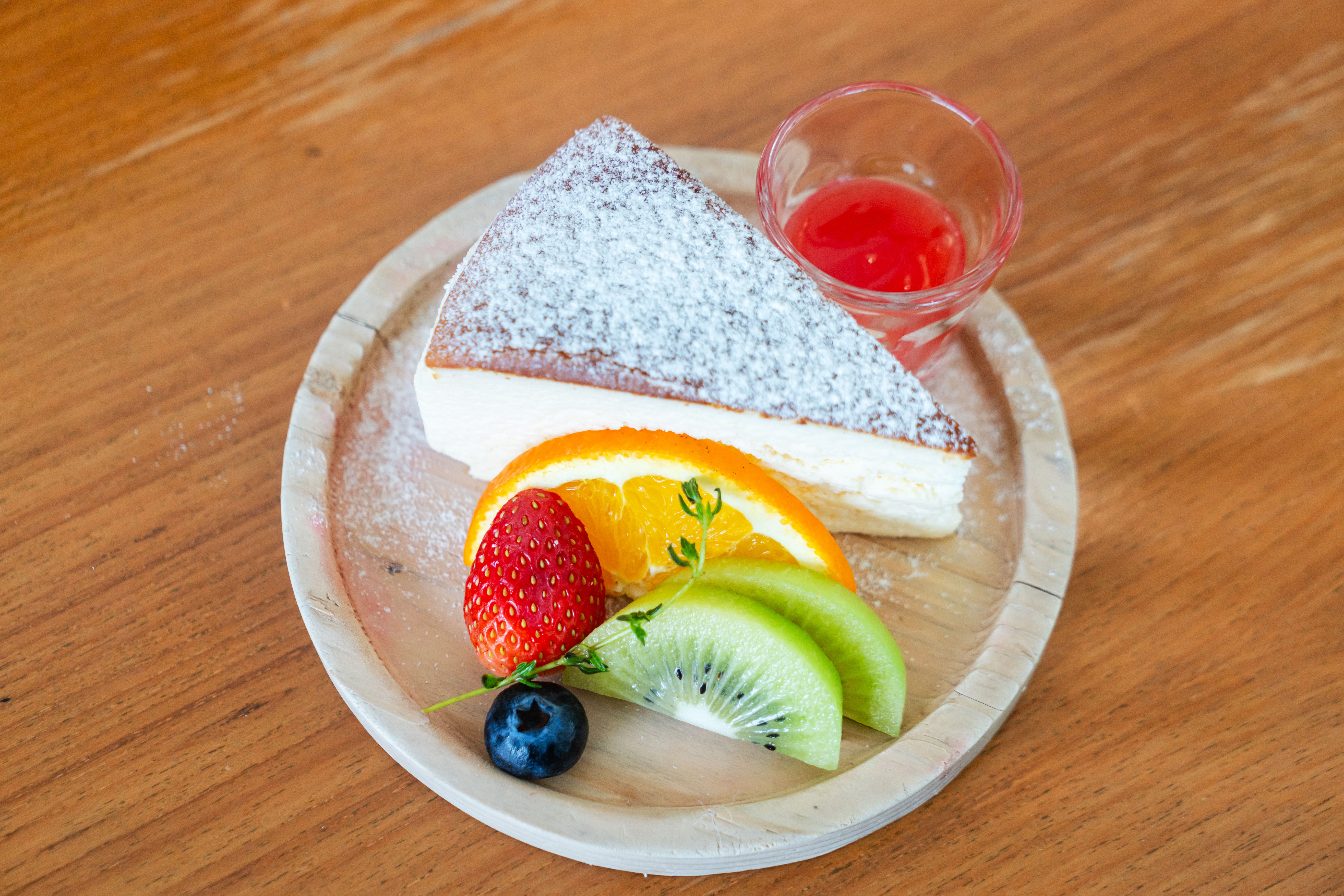 Silken tofu cheesecake topped with tropical fruit slices on a rustic wooden table